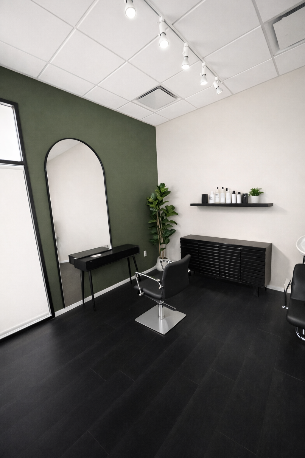Touch & Go Express Color Studio interior featuring modern styling chair, arched mirror, and elegant green accent wall